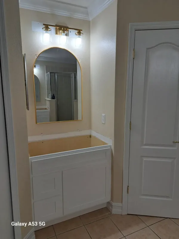 Bathroom vanity install with mirror, light fixture, sink fixture and cabinet handles — before